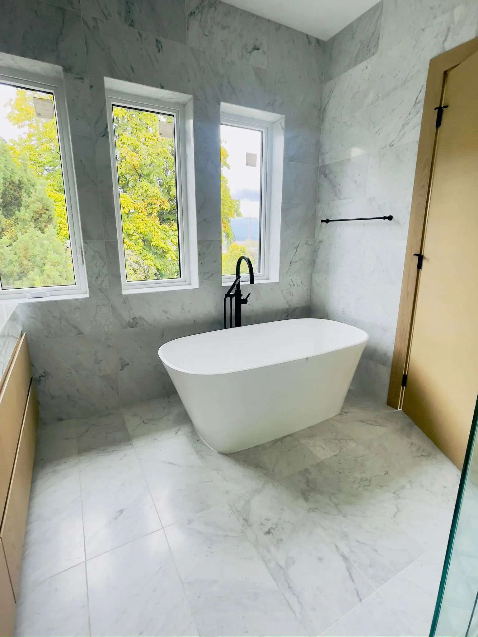 A freestanding bath in a finished marble bathroom, supplied by a floor-mounted filler.