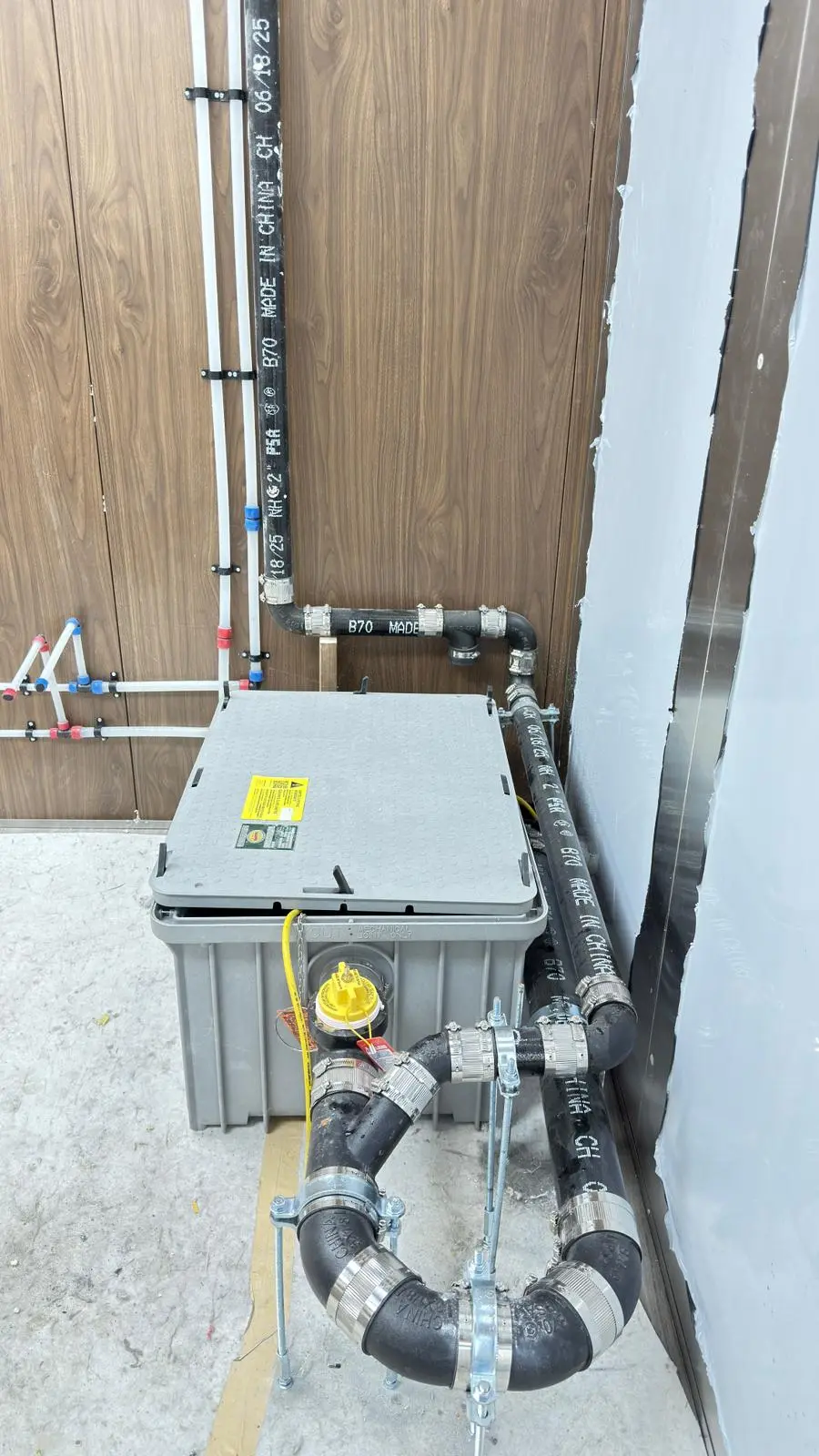 A grease interceptor piped in under a commercial kitchen.