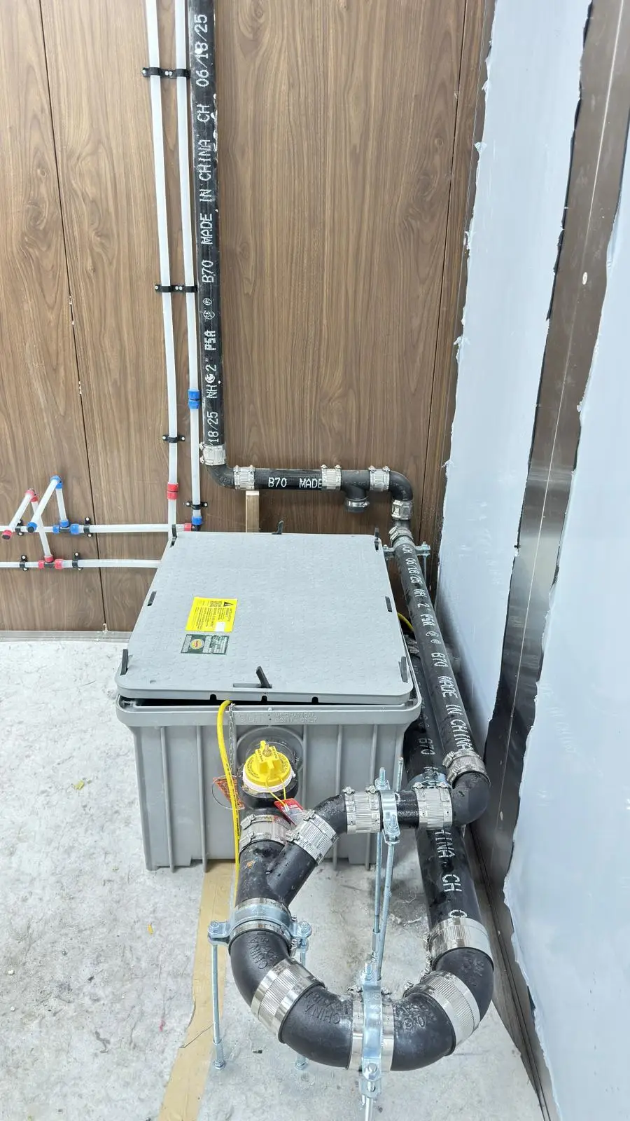 A grease interceptor piped in under a commercial kitchen.