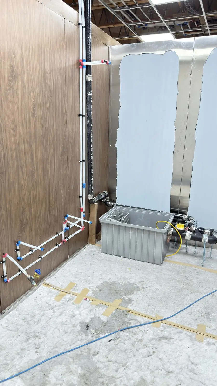 Kitchen supply lines roughed in beside a newly set grease interceptor.