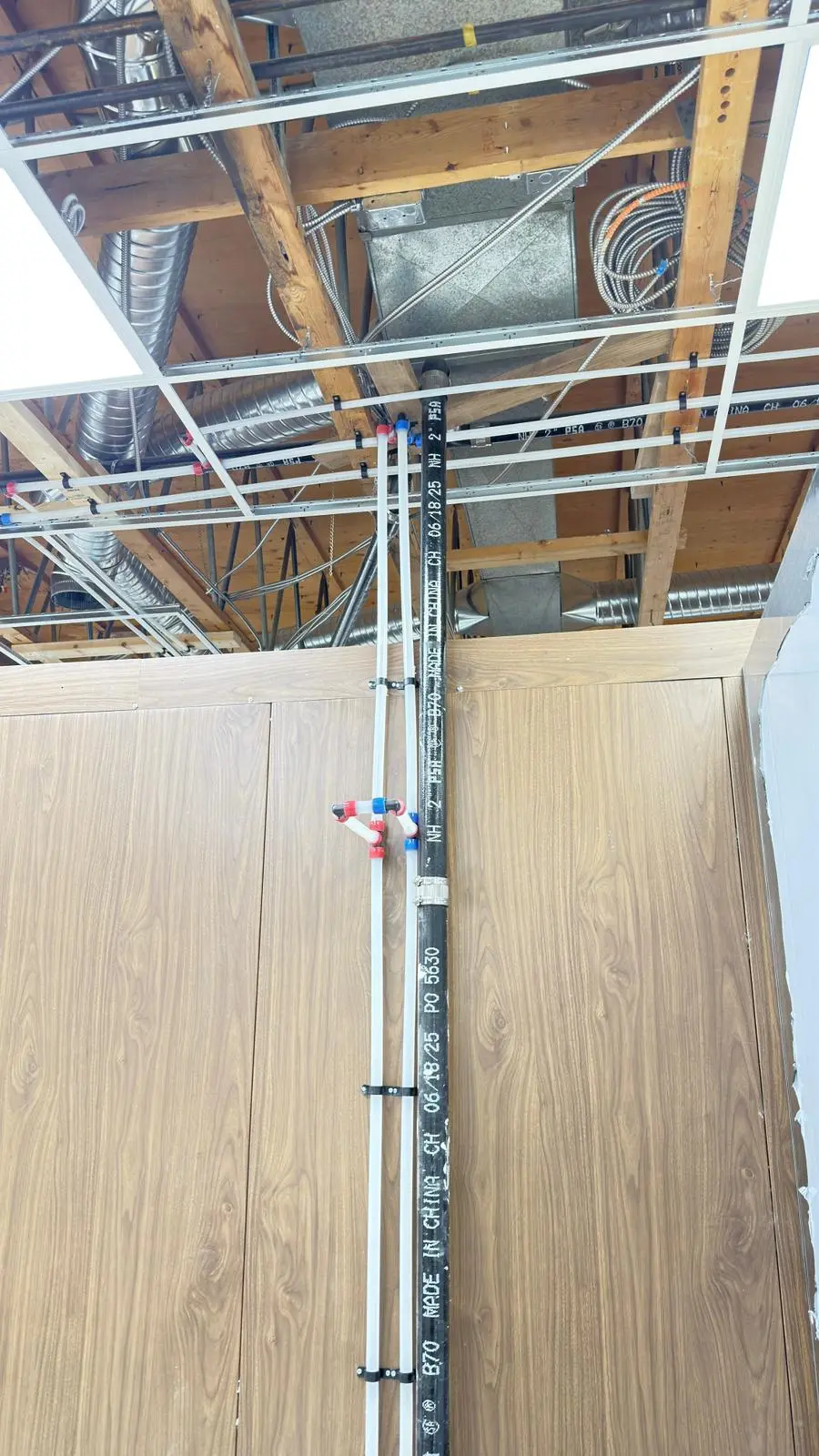 Supply lines carried overhead through the open ceiling of a fit-out.