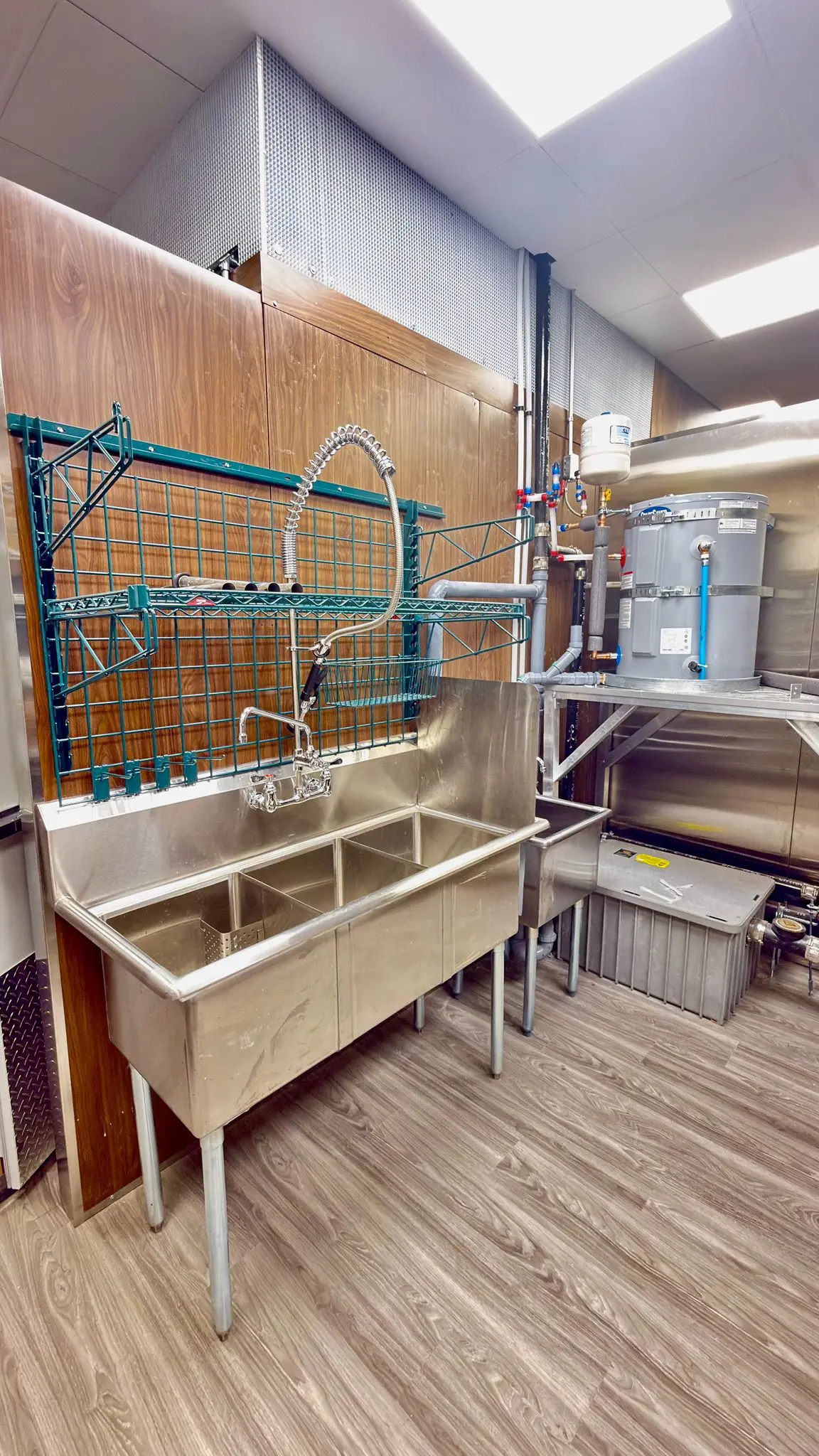 A commercial kitchen sink line with the water heater piped in alongside.