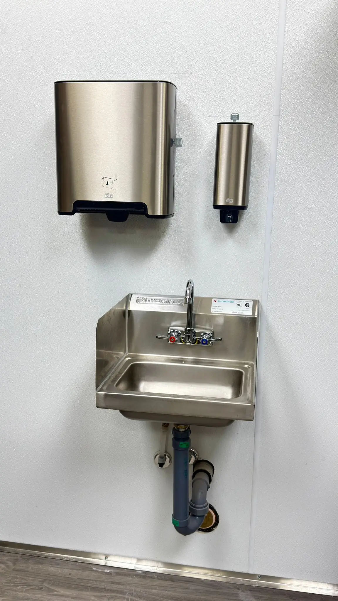 A stainless hand sink mounted to code with its trap left accessible.