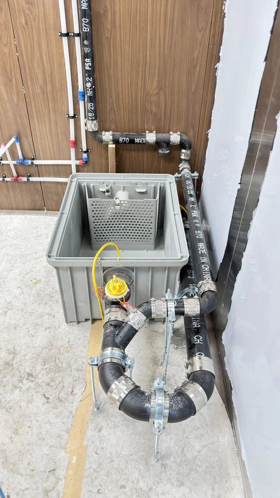 A grease interceptor piped into the drainage line under a commercial kitchen.
