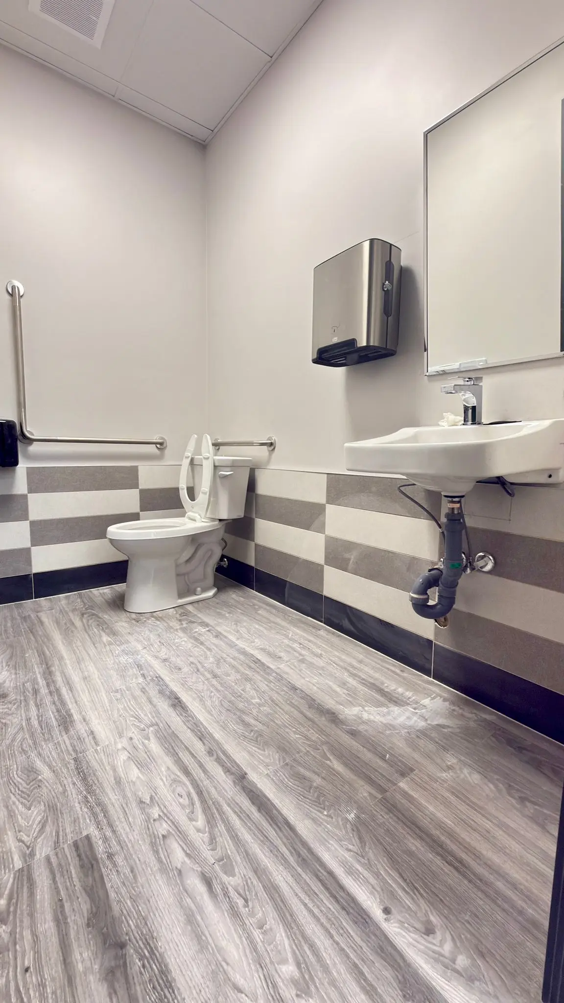 An accessible washroom with a grab rail and a wall-hung basin.