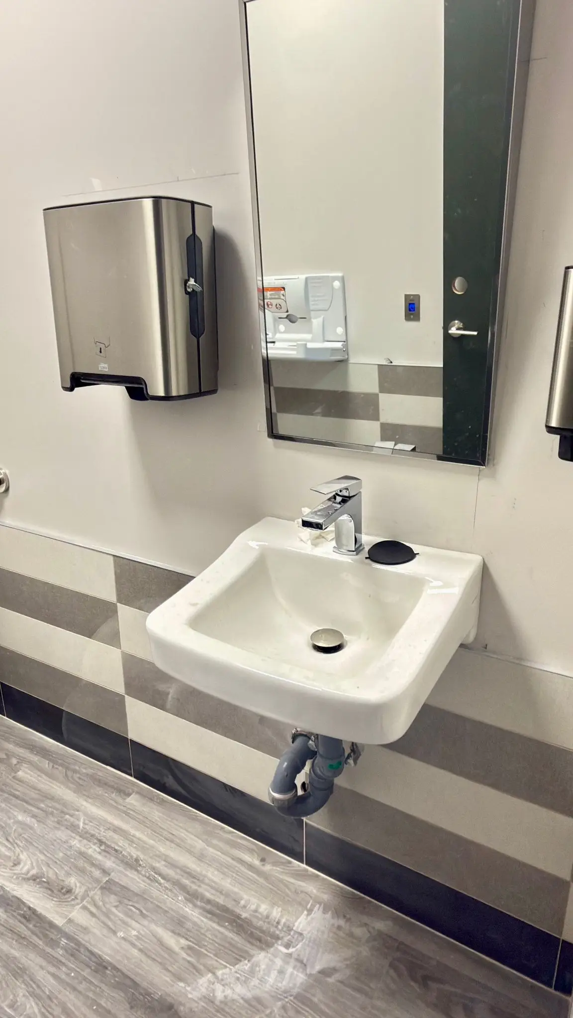 A wall-hung basin with its trap and supplies left exposed for service.