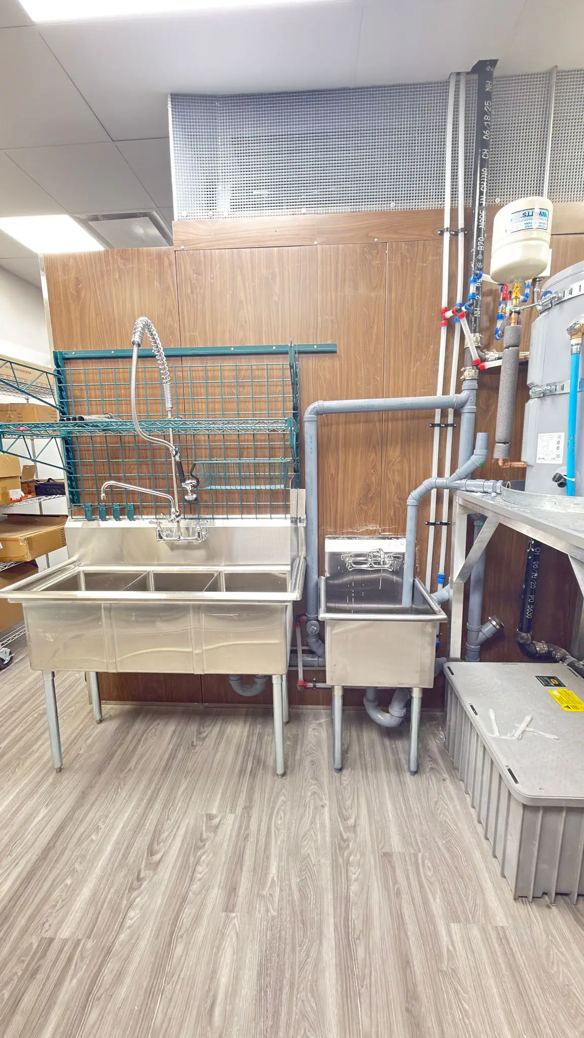 A three-compartment sink and pre-rinse column set up in a new kitchen.