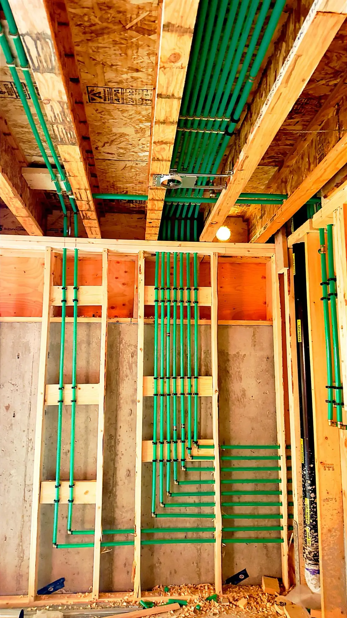 Heating and supply lines sleeved through the joists of a new build.
