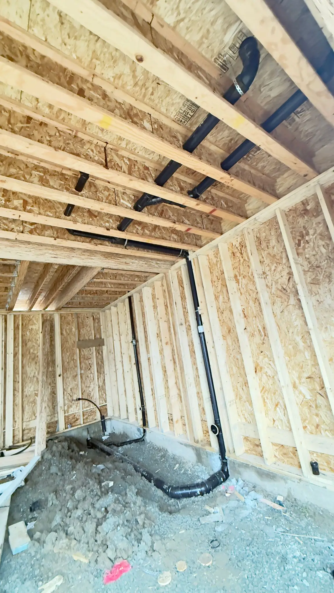 Black ABS drainage set into the floor of a new build before the pour.