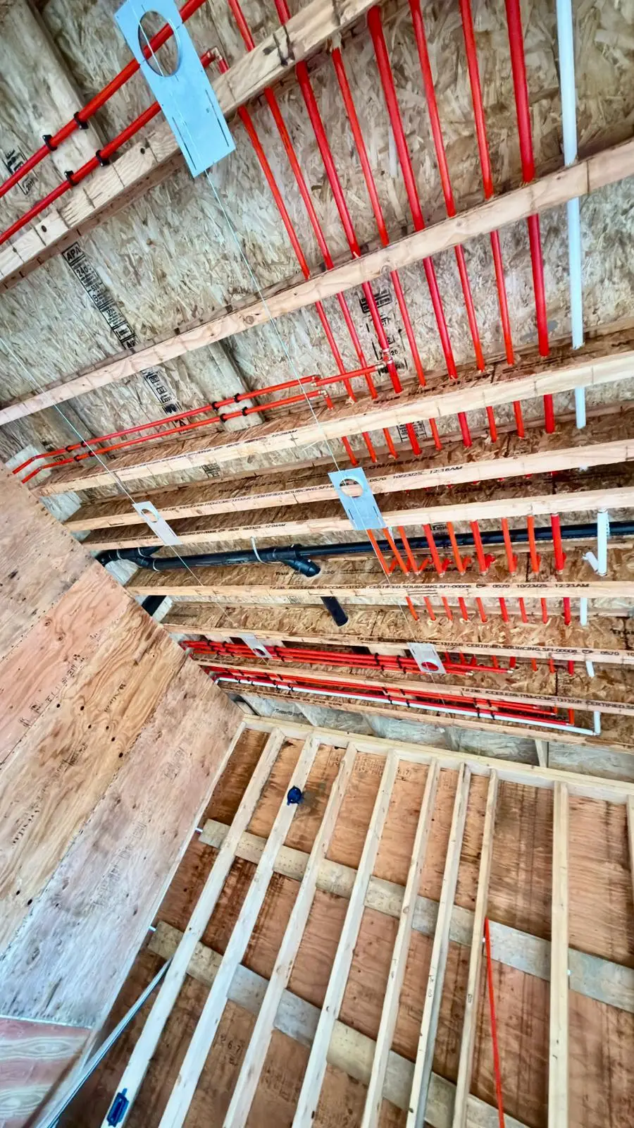 Supply lines and drainage run overhead before the ceiling is closed.