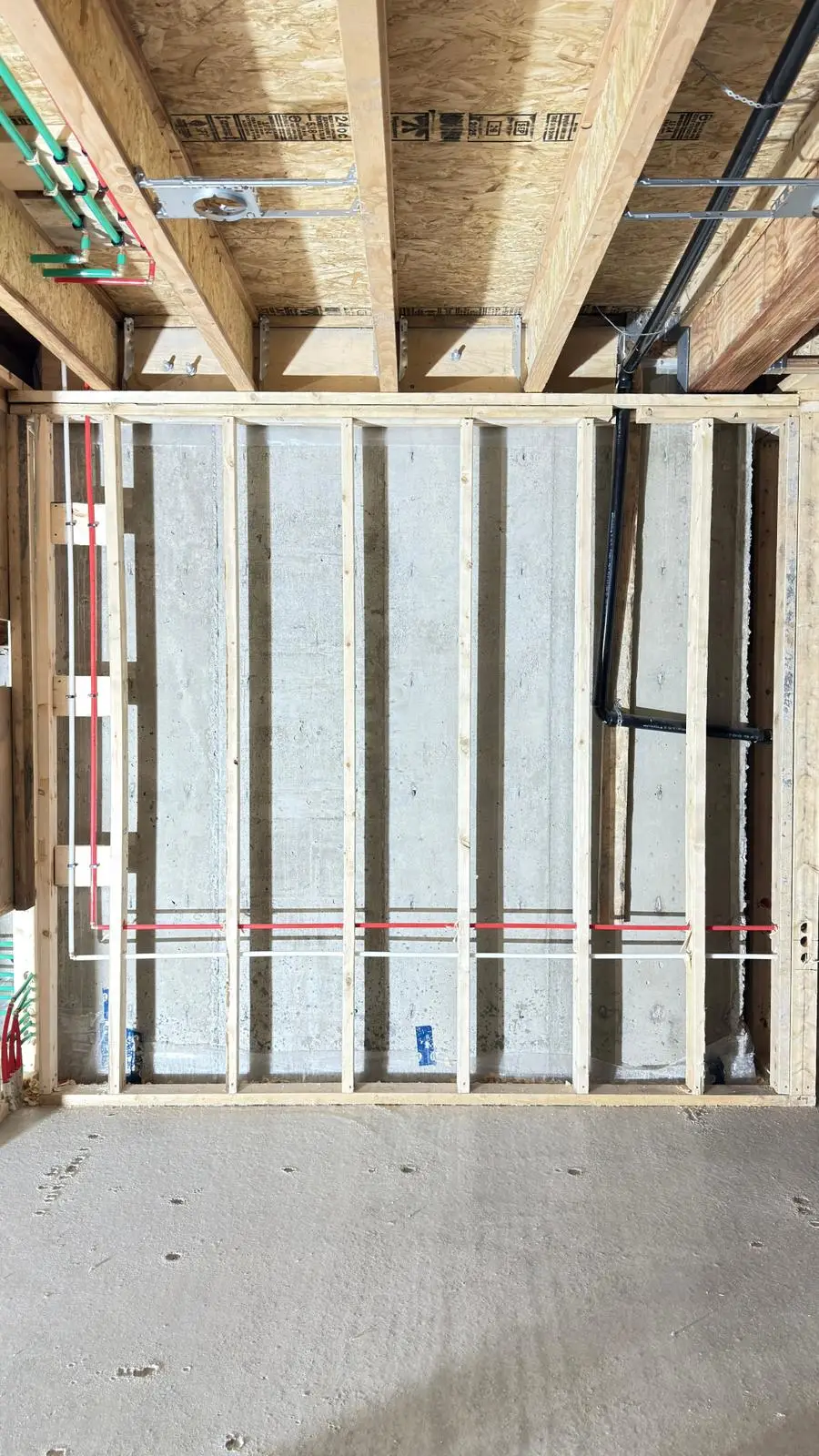 Radiant heating lines run low through the framing before the wall closes.