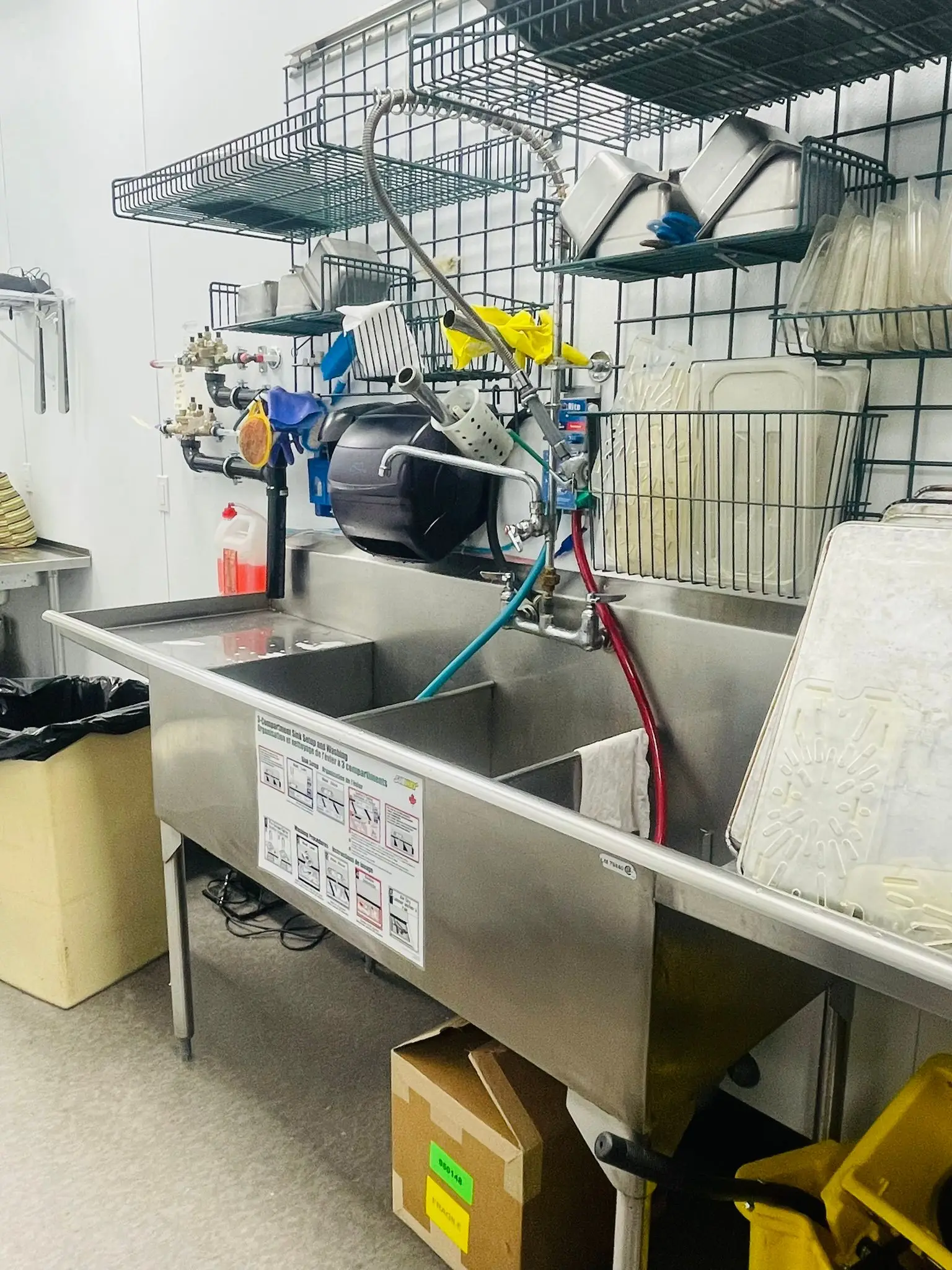Commercial sinks and their supply lines fitted out in a restaurant kitchen.