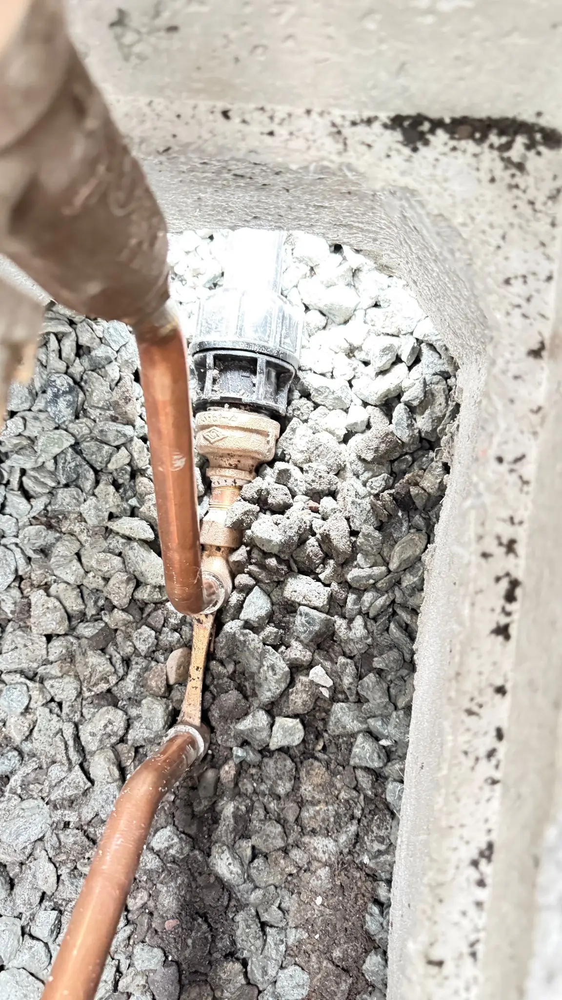 A copper water service connection made up in an open trench.