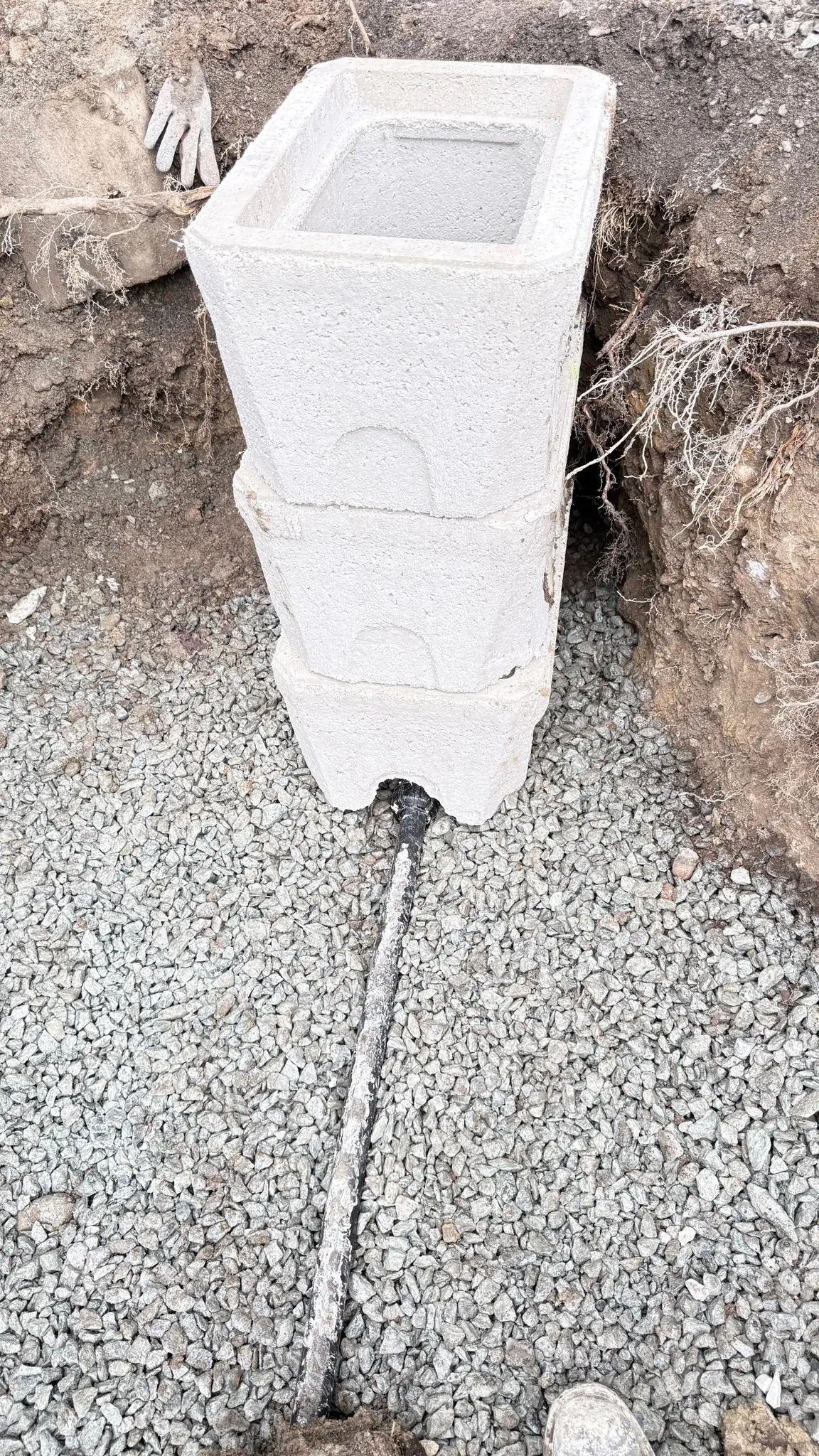 A meter chamber with the new service line running out across the gravel.